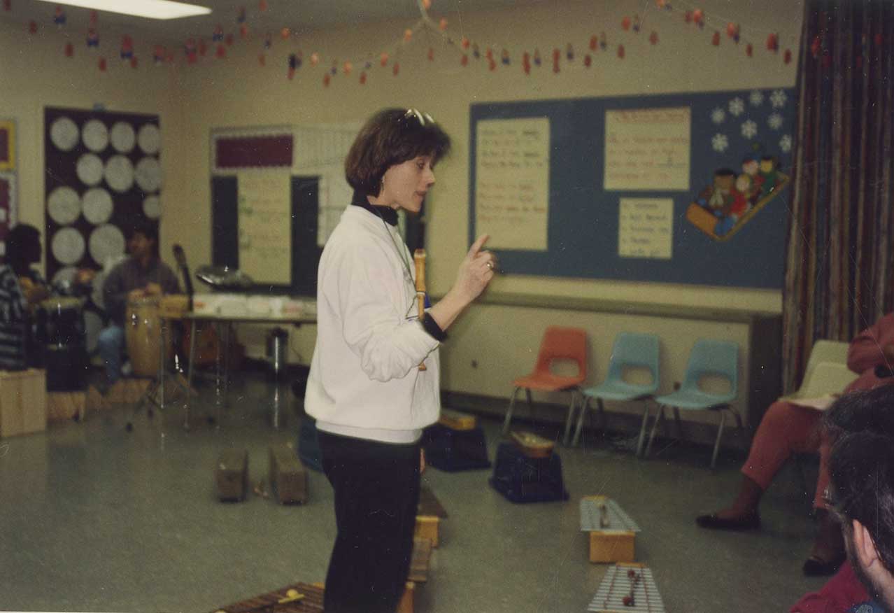 Individual teacher stands in a classroom.