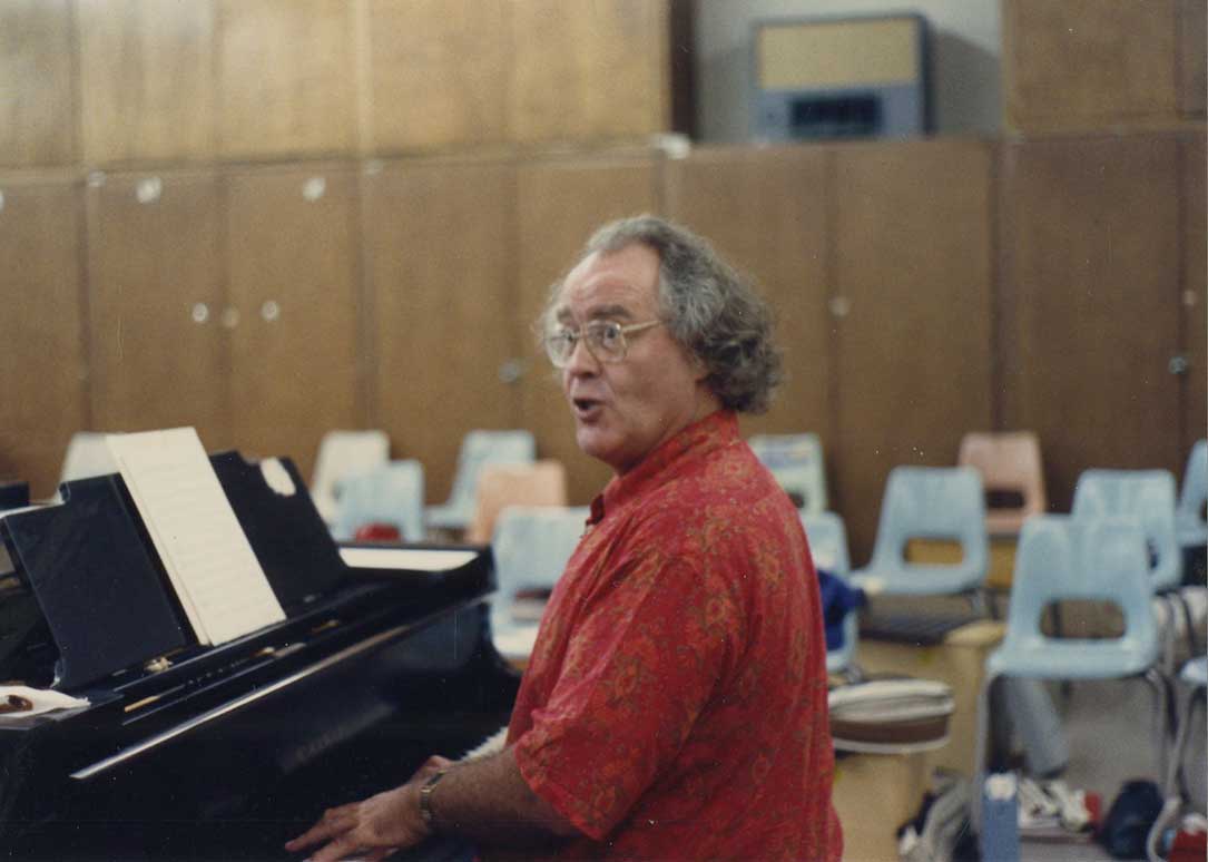 Adult male pianist sits at a piano playing music.