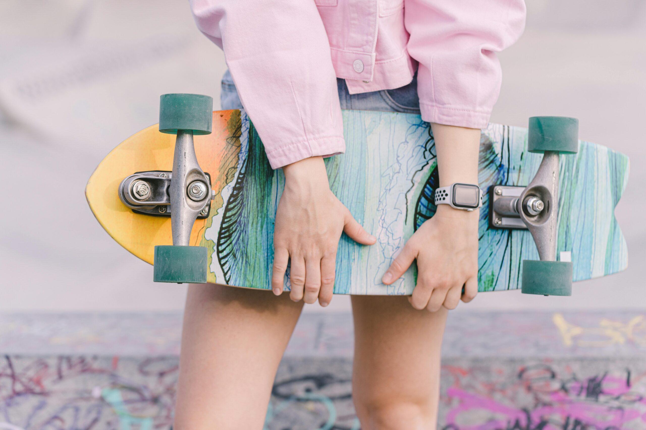 Close-up image of a trendy skater holding a vibrant skateboard, showcasing style and youth culture.