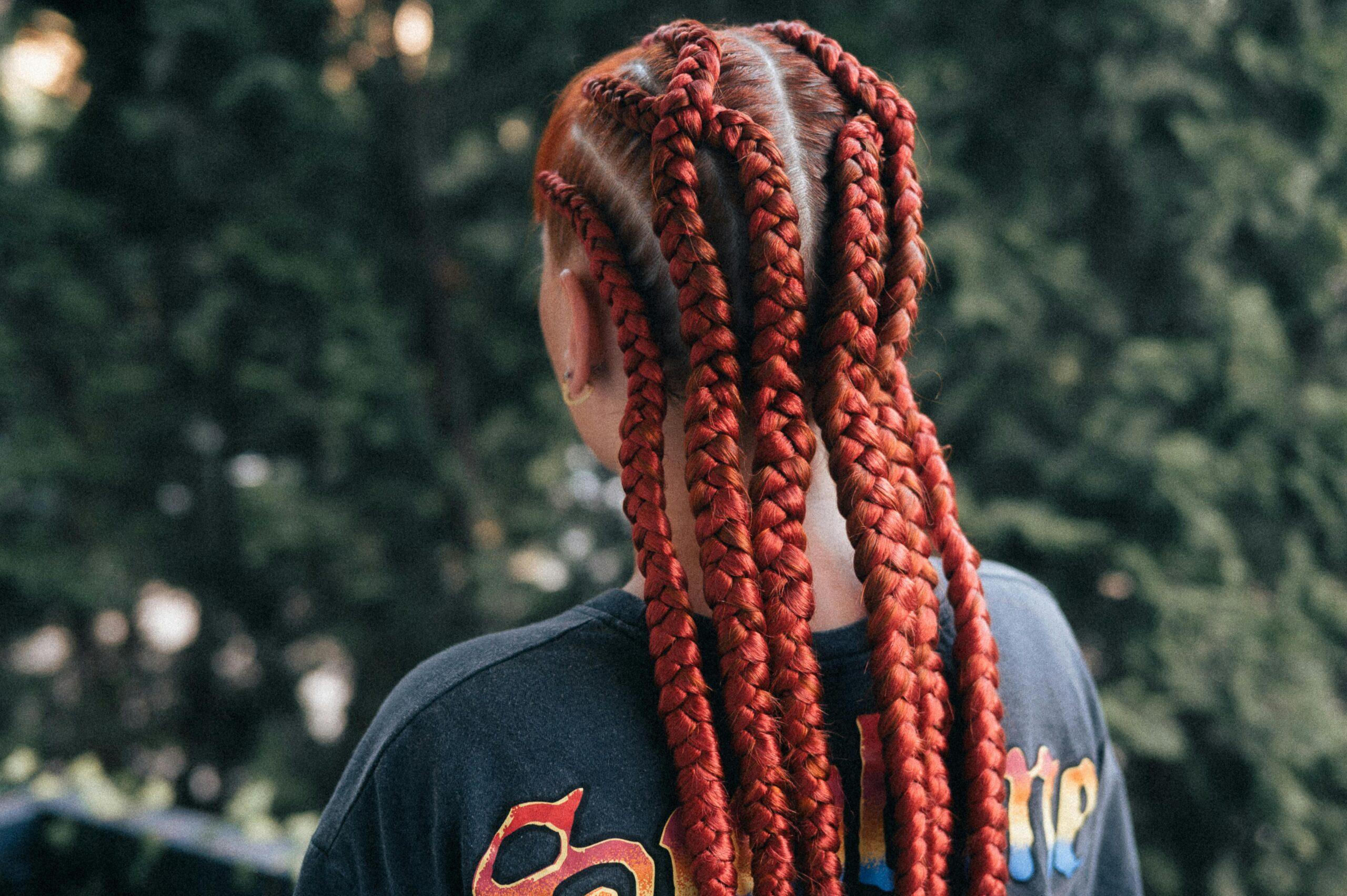 Close-up of vibrant red braids on an adult outdoors.