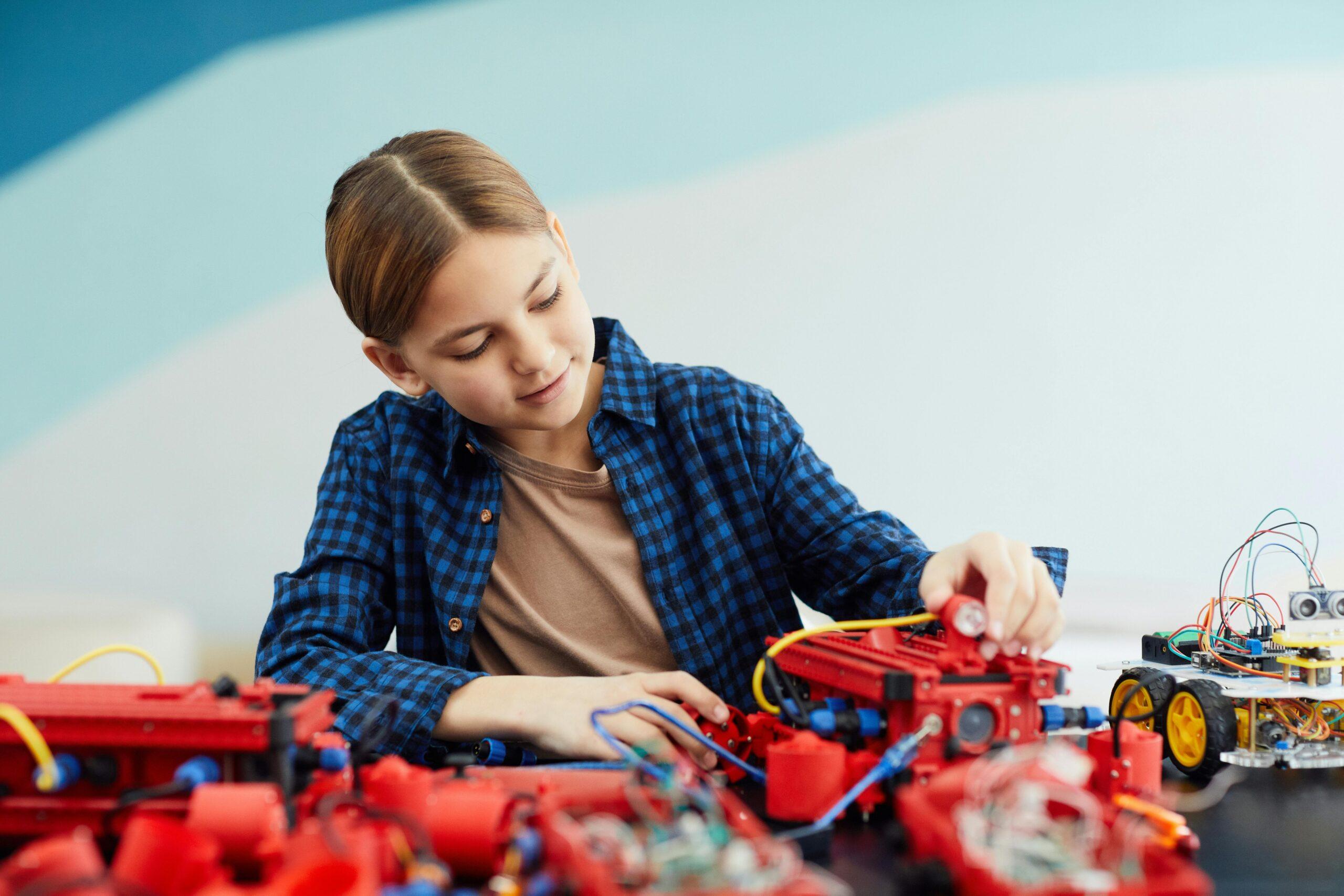 A teenage girl engaged in assembling a robotics project with various electronic components.