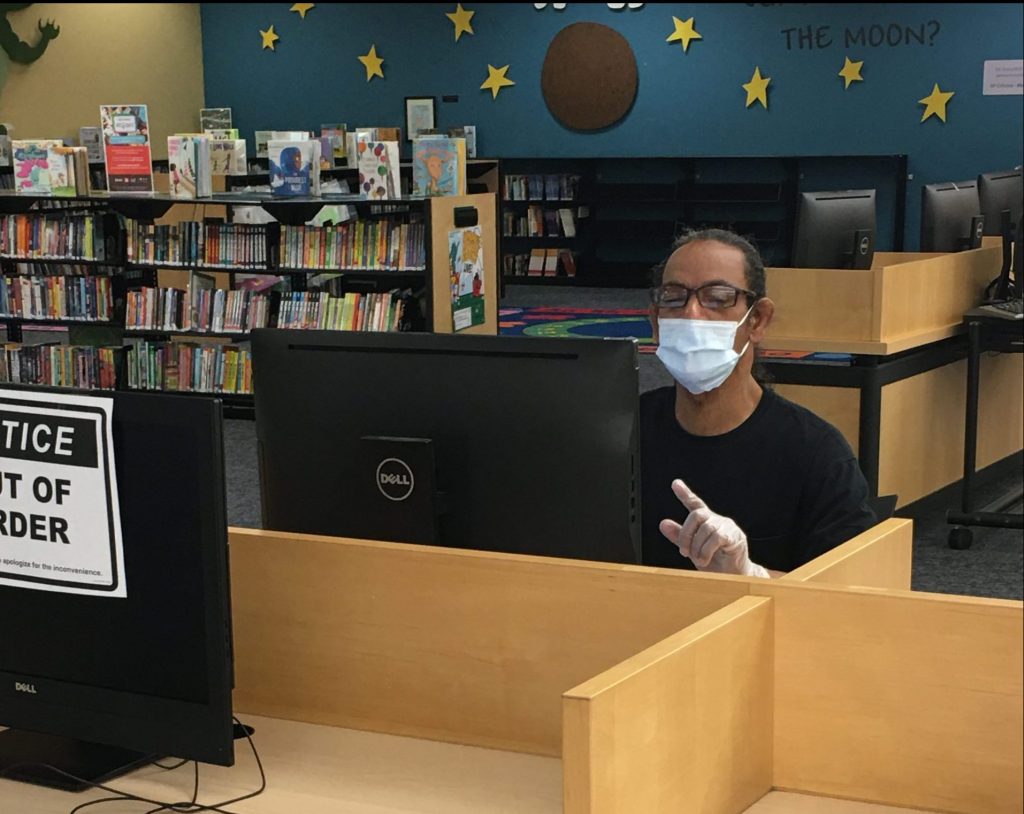 Library patron in mask at a library computer.