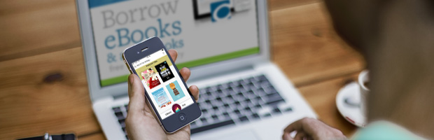 Customer using a phone and laptop to access electronic materials.